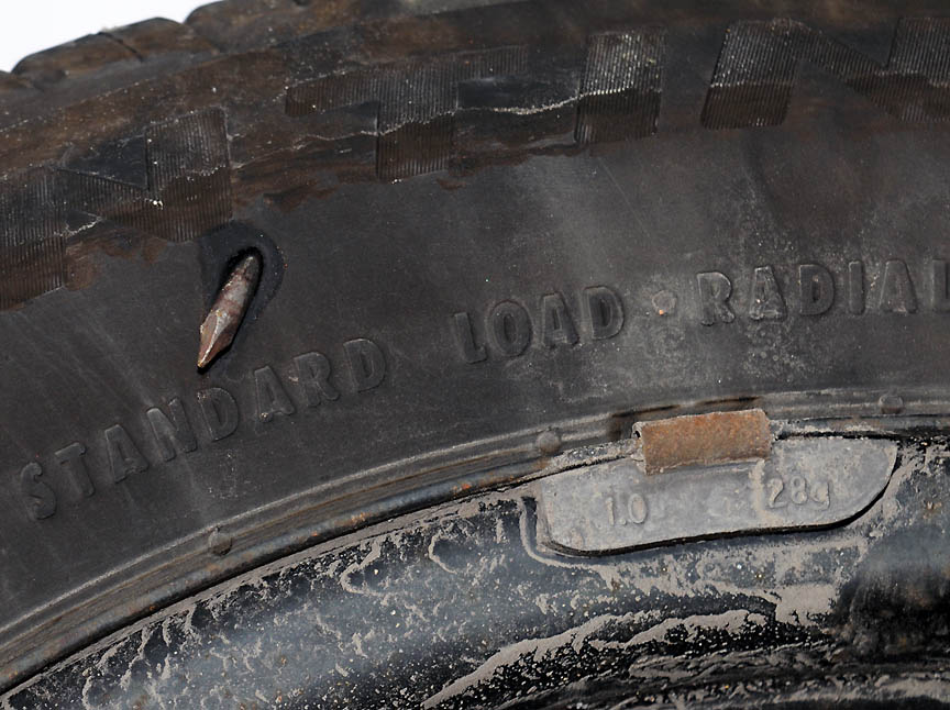 Close-up view of a flat tire with a nail in it